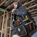 Man carrying Klein Tools Tradesman Pro™ 10" Tool Tote, filled with hand tools